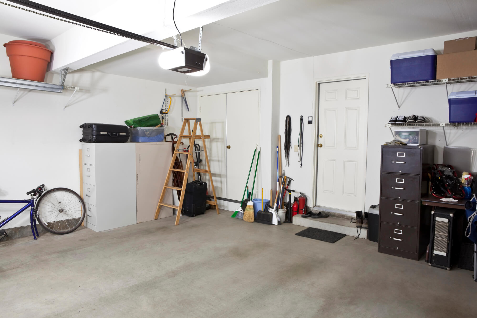 Interior view of garage with garage door opener and storage gear in background